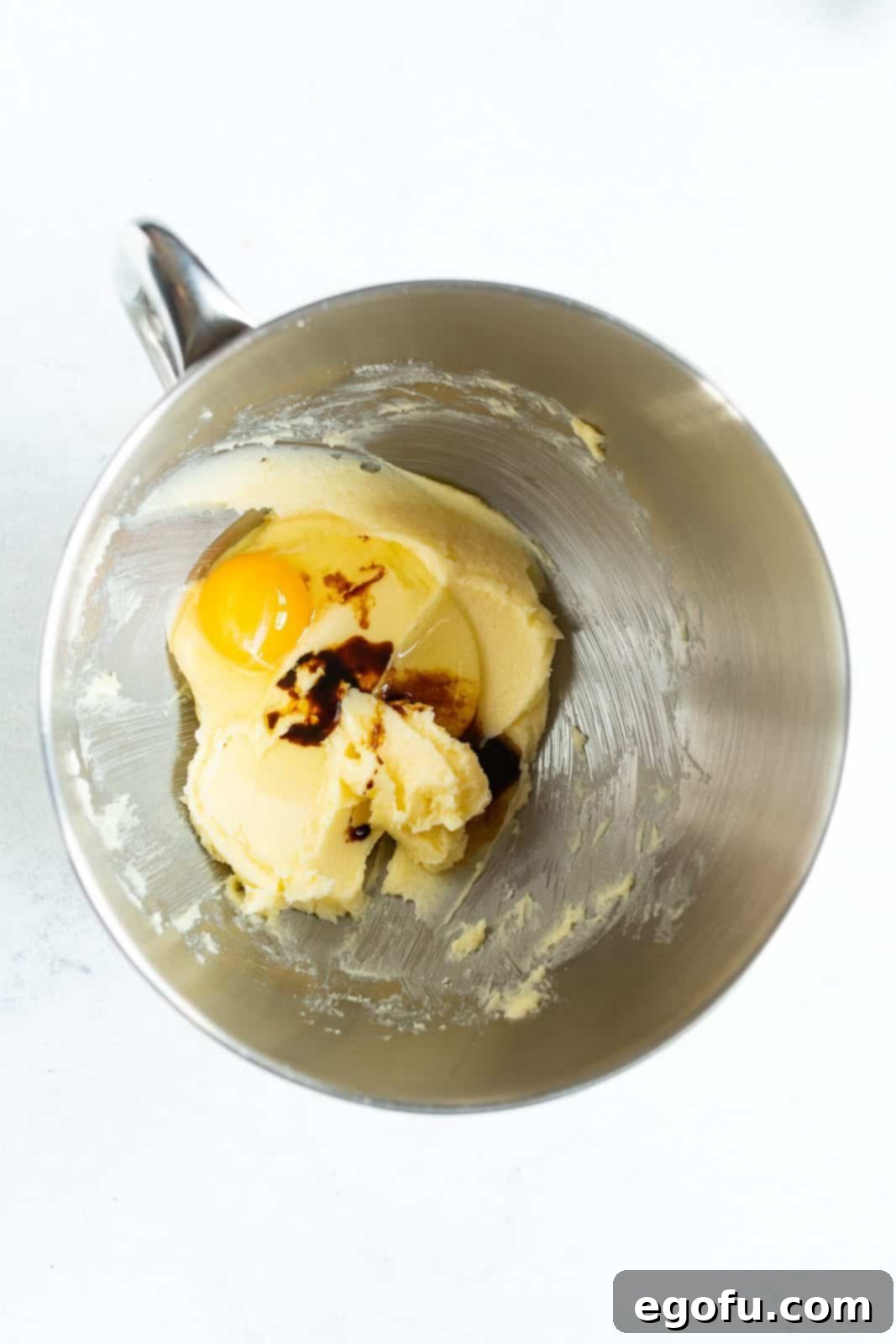 Egg and vanilla added to butter and sugar mixture in bowl of stand mixer.