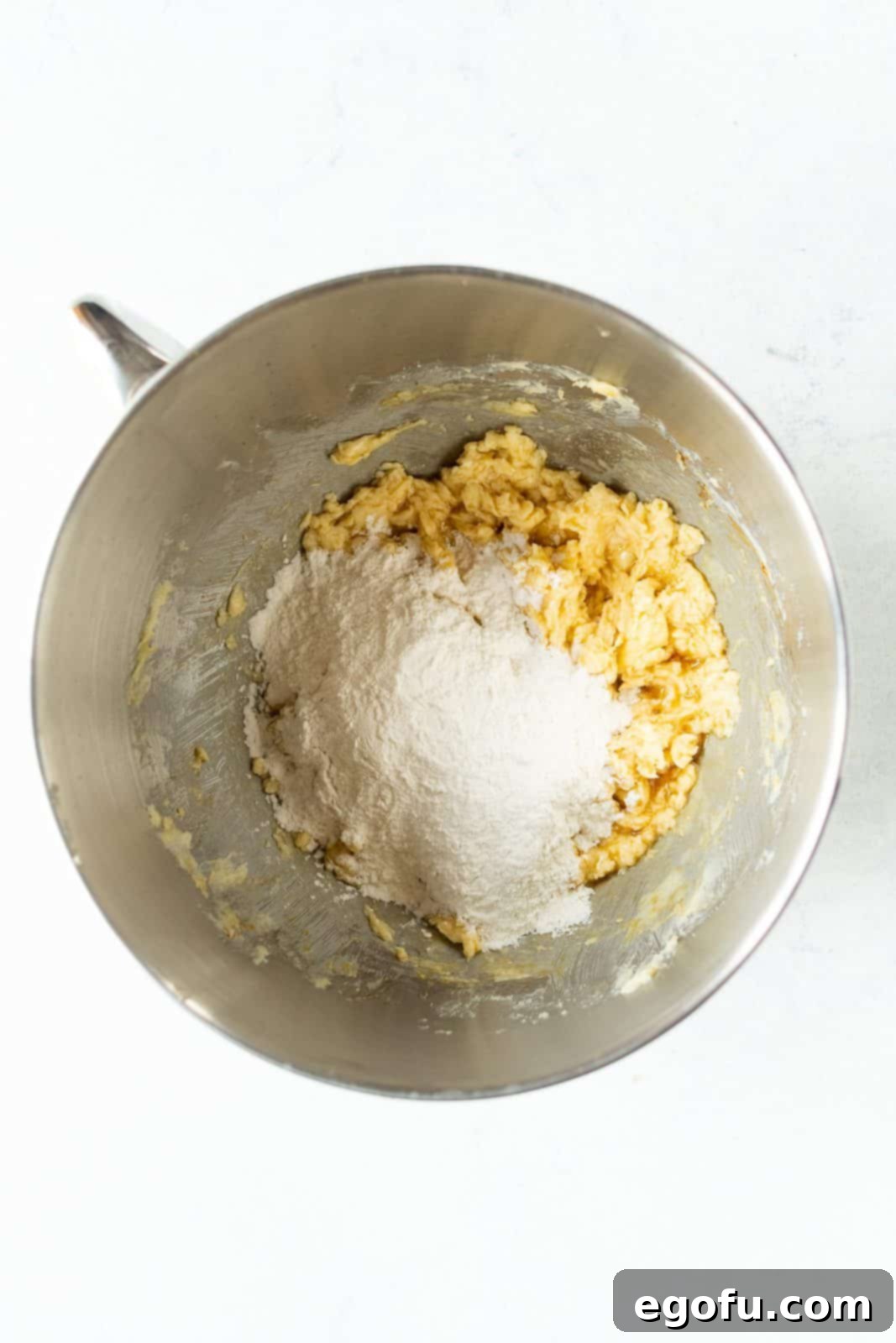 Flour mixture added to butter mixture in bowl of stand mixture.