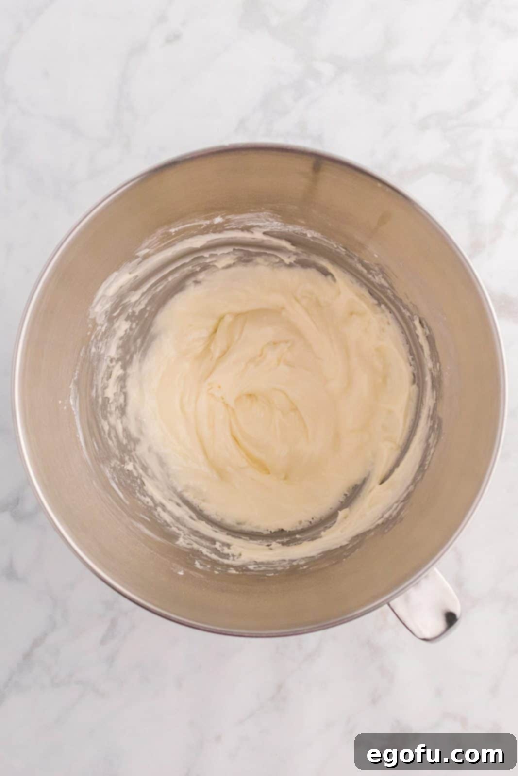 Homemade buttercream frosting being mixed in a stand mixer bowl.
