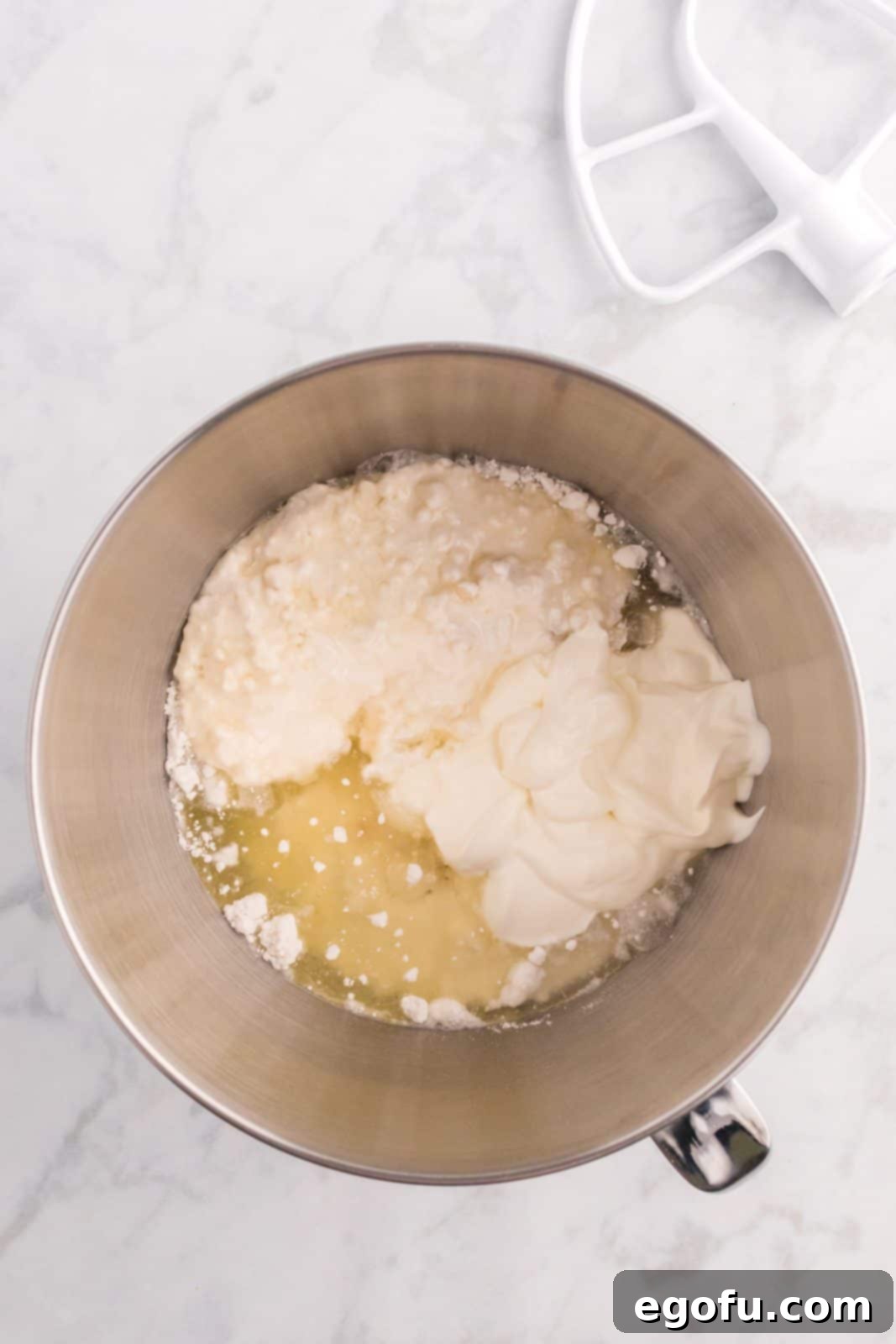 White cake mix, water, egg whites, vegetable oil, sour cream, and clear vanilla extract in a stand mixer bowl.