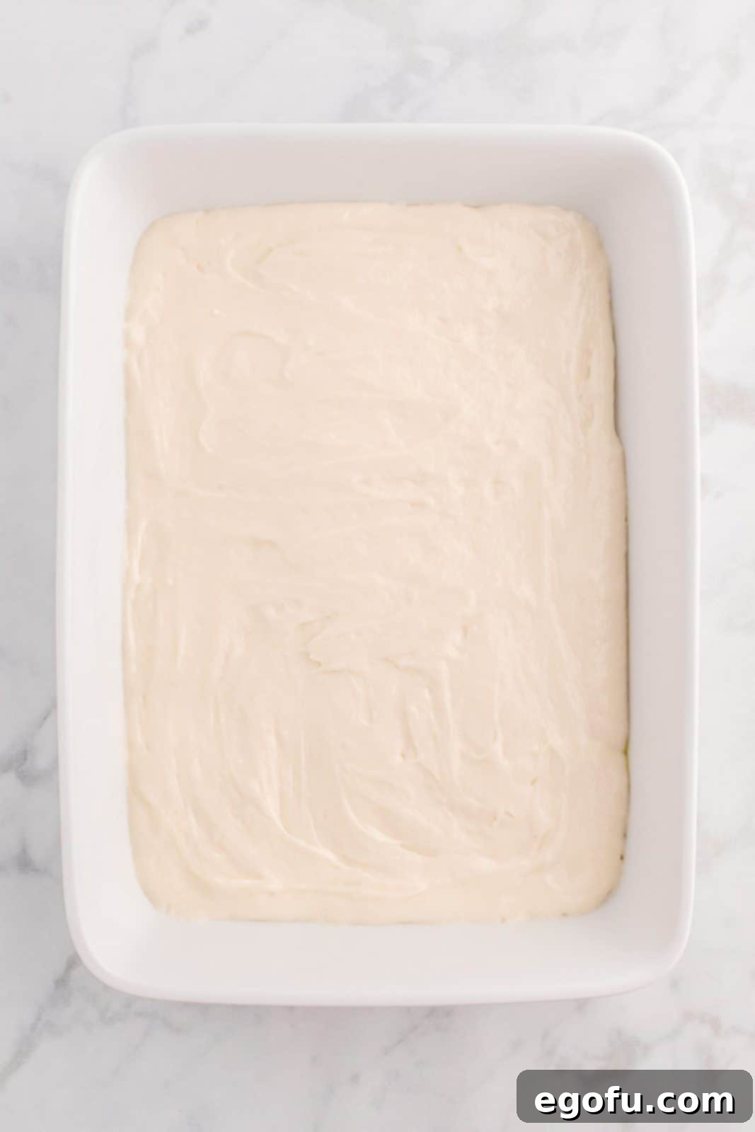 2 cups of white cake batter poured into the prepared baking dish.