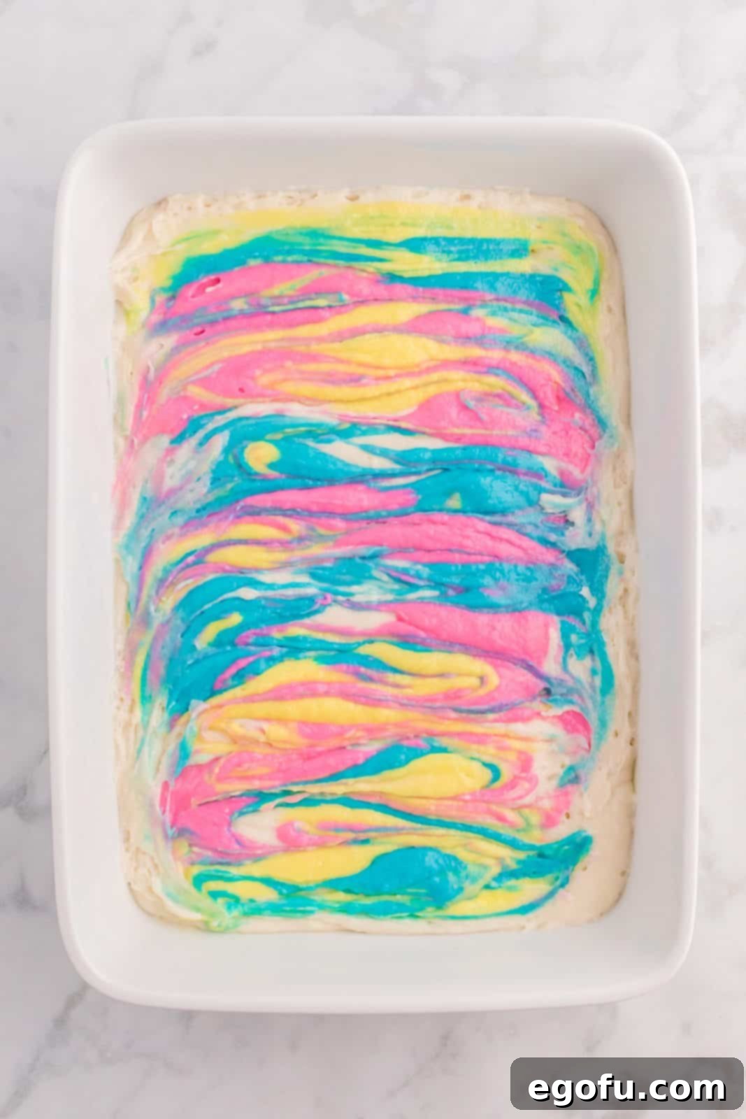 Colored cake mix gently swirled into the white cake batter with a butter knife.