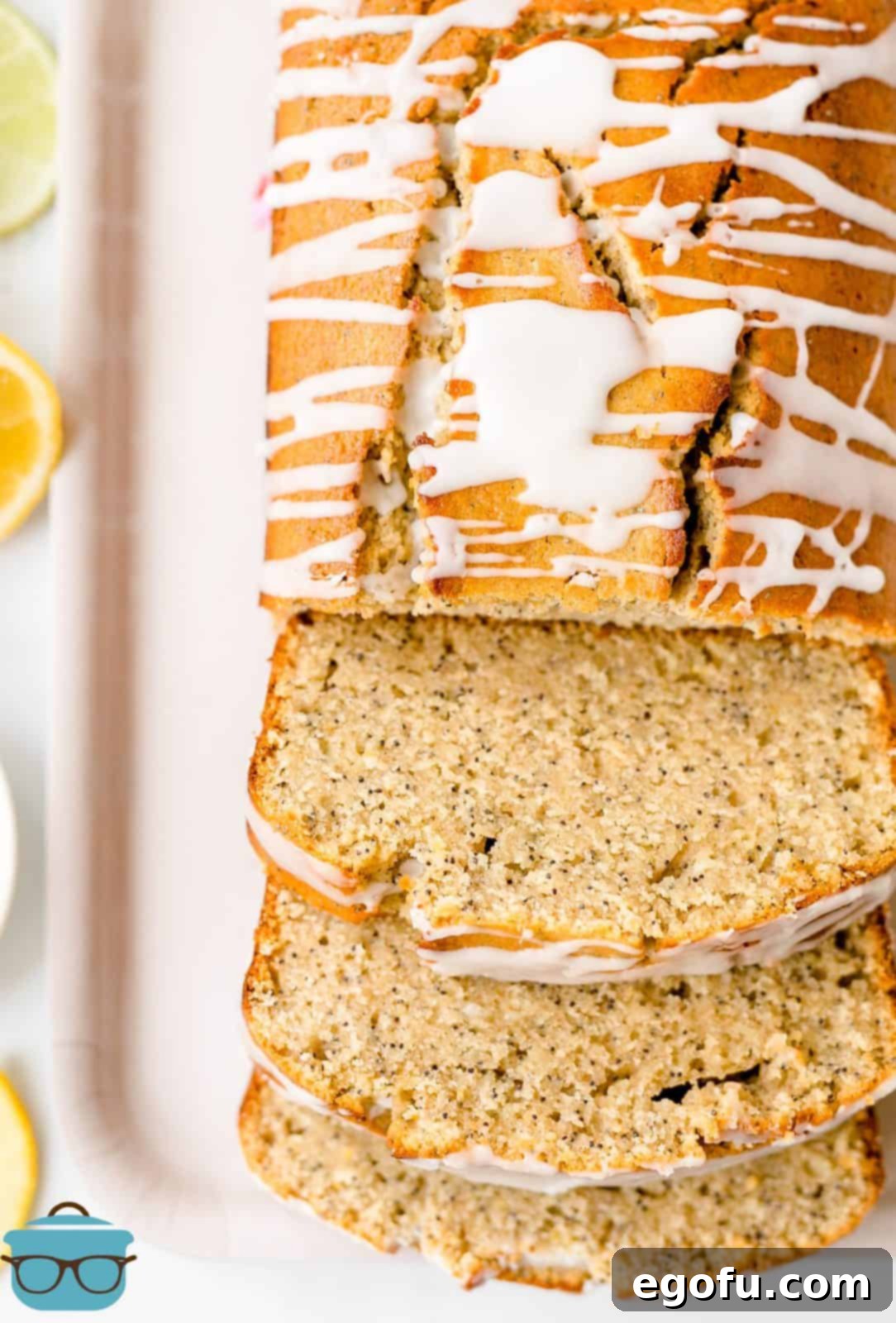 Overhead of sliced Lemon Poppy Seed Bread on platter with whole bread behind slices.