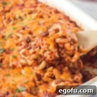 Square image of a serving spoon lifting out some of the Cheeseburger Macaroni Casserole.