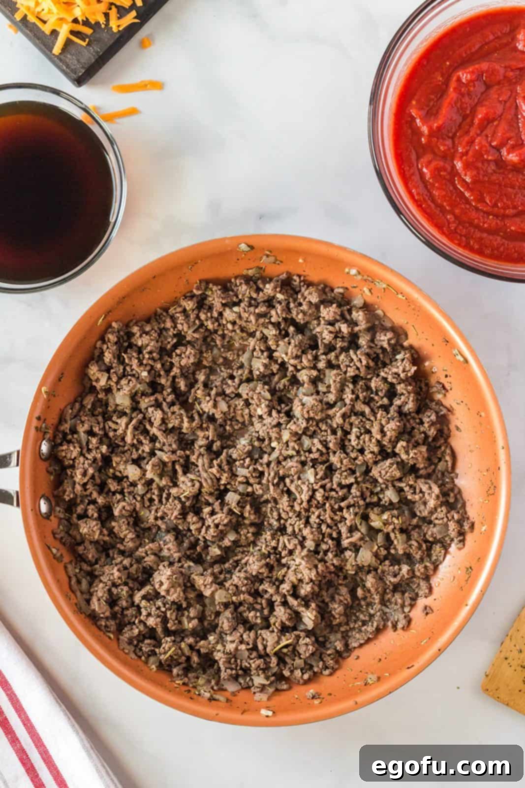 Ground beef cooking in the frying pan with onions and seasonings, browning evenly.