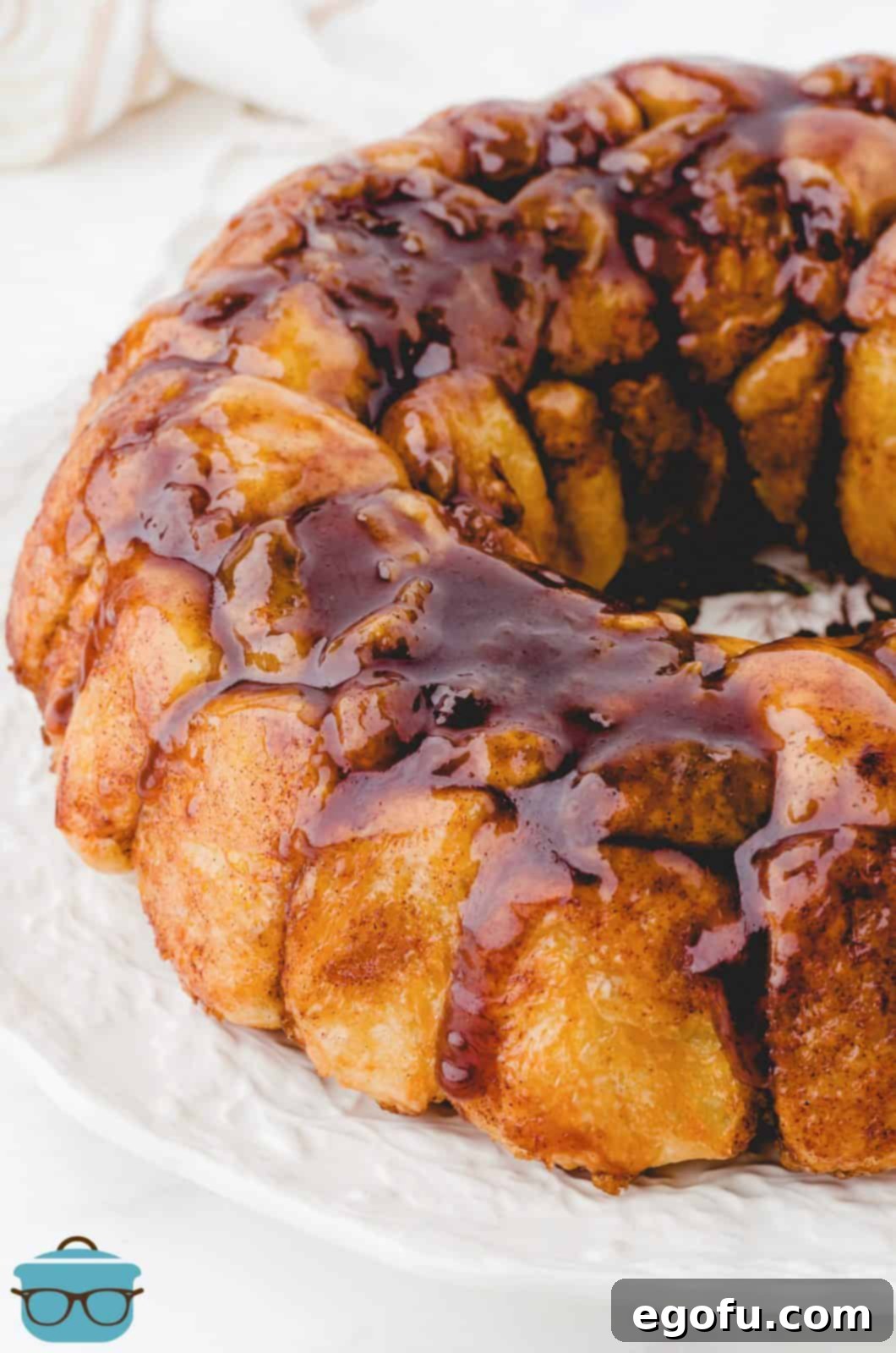 Close up of side of Easy Monkey Bread on white platter showing gooey topping.
