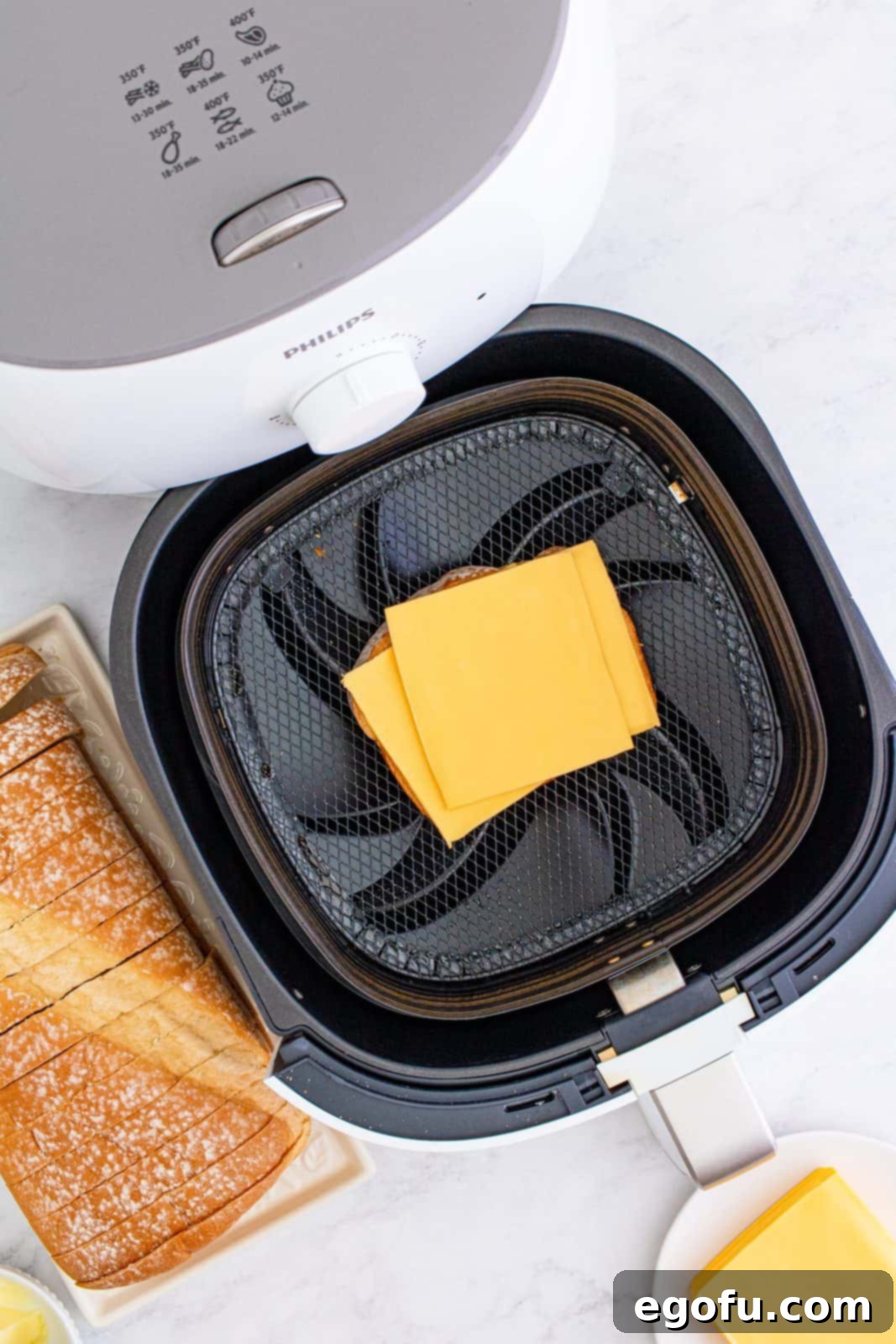 Air Fryer's Golden Crispy Grilled Cheese 7 Cheese added to top of bread in air fryer basket.