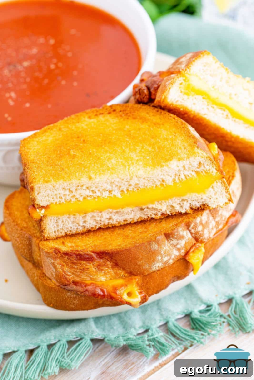 Air Fryer's Golden Crispy Grilled Cheese 10 Stacked Air Fryer Grilled Cheese on plate with side of tomato soup.