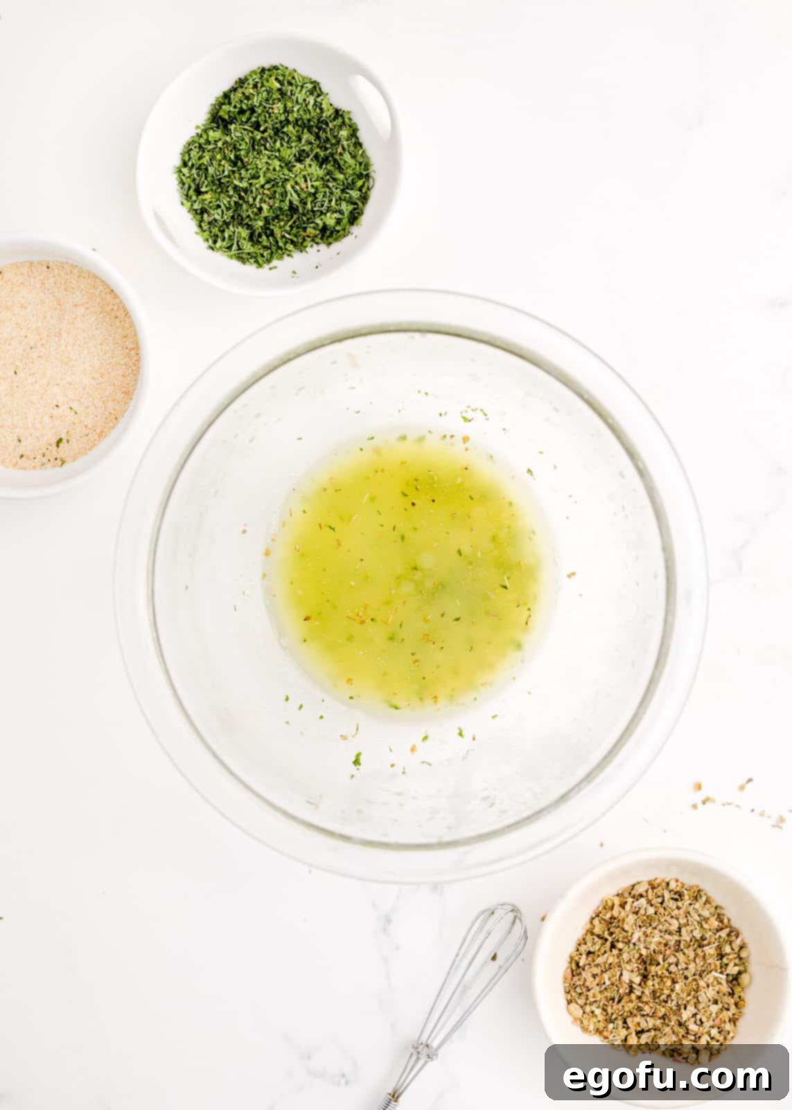 Melted butter and seasonings (garlic powder, oregano, parsley) stirred together in a bowl.