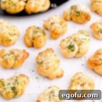 Finished Easy Garlic Knots on a white plate, topped with cheese, a square image suitable for recipe cards.