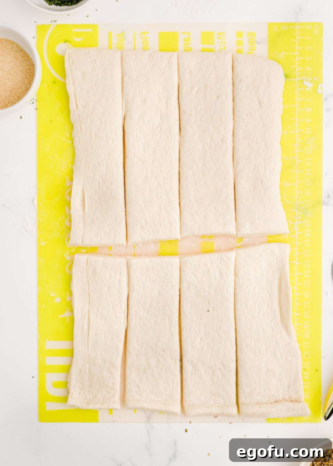 Pizza dough cut into 8 strips, ready for further division.