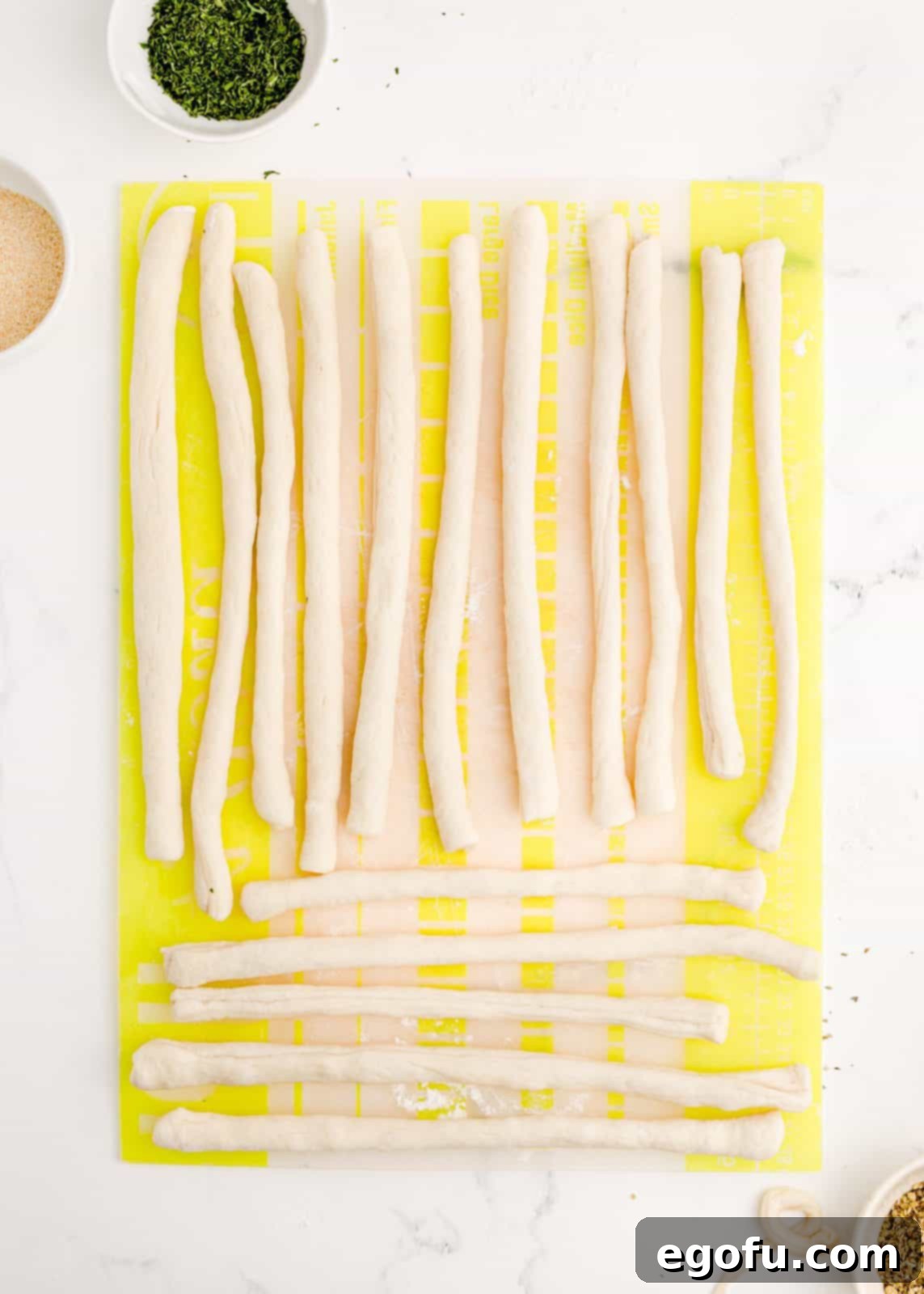 Individual pizza dough strips rolled into 8-inch ropes, ready to be tied.