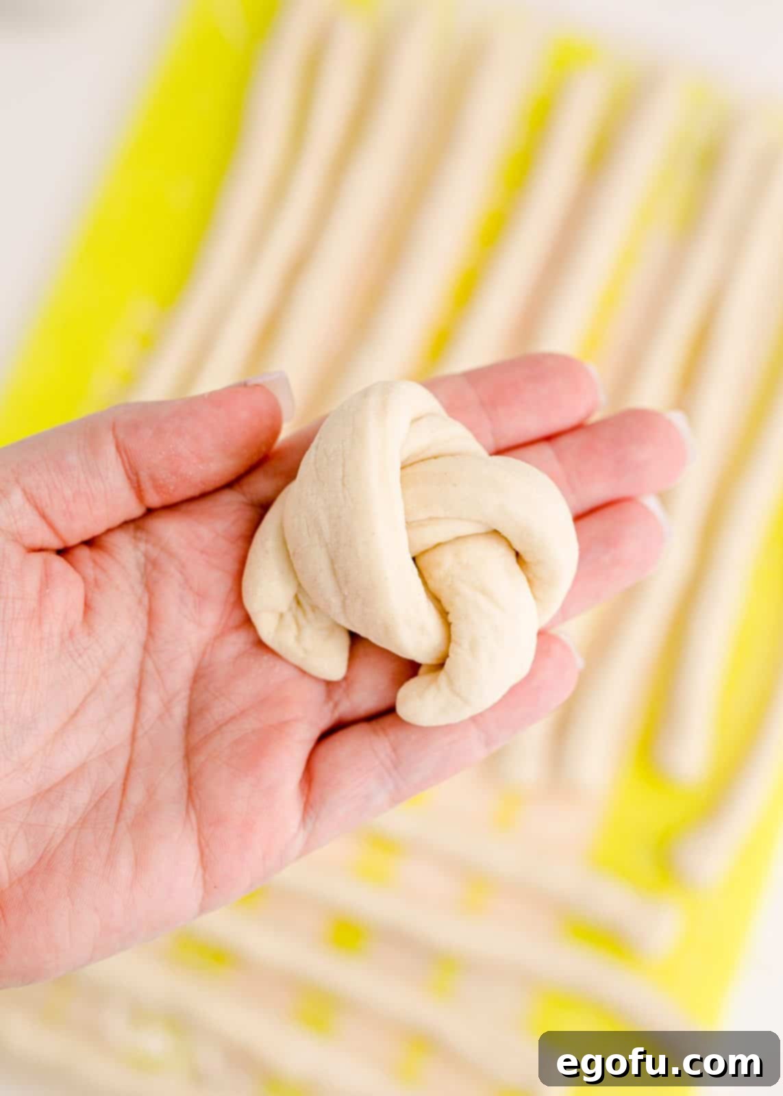 A single dough rope tied into a simple knot, demonstrating the knotting process.