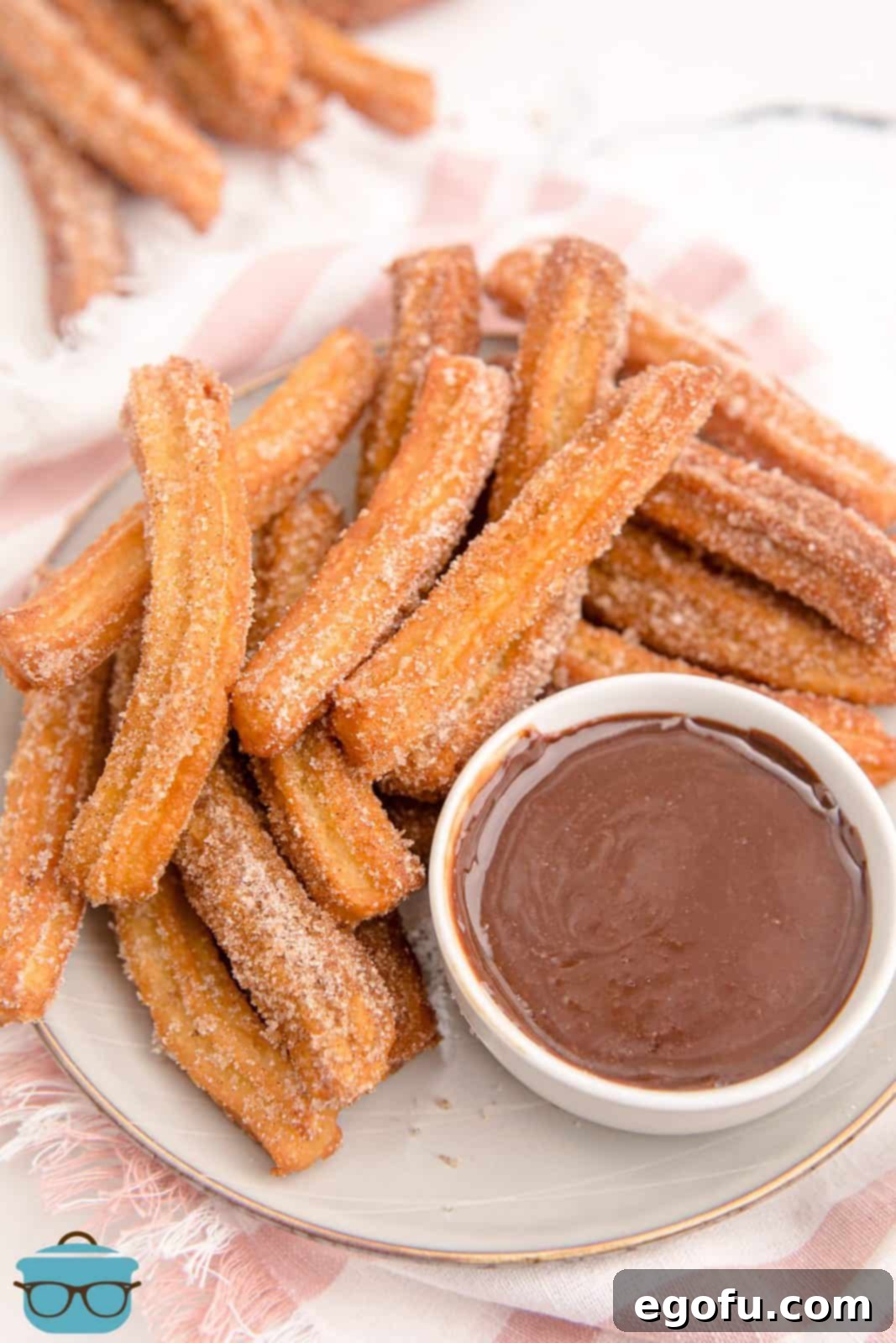 Layered Homemade Churros on a white plate overhead with rich chocolate dipping sauce, ready to be enjoyed.