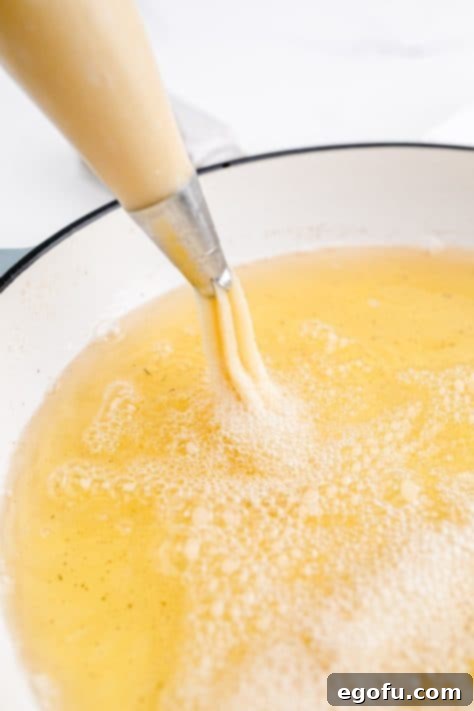 Churros being piped into hot oil.