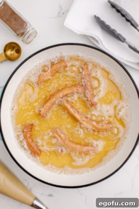 Churros flipped in oil.