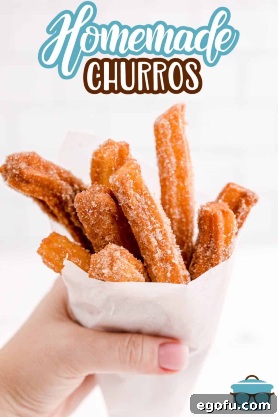 A hand holding a bunch of freshly made Homemade Churros wrapped in parchment paper, presented beautifully for a Pinterest image.