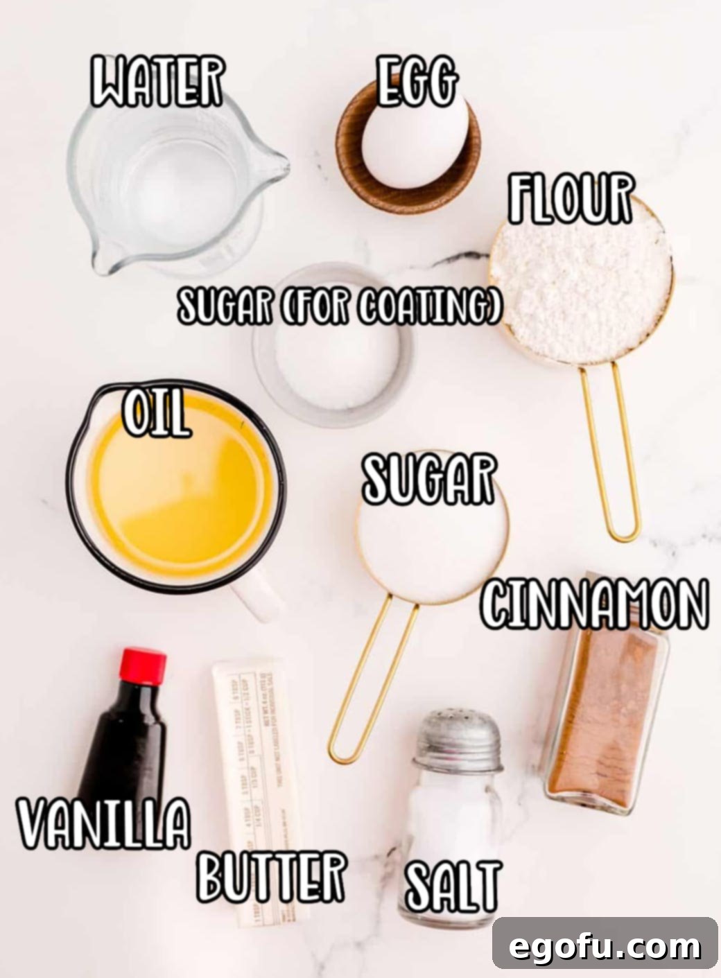 A collection of fresh ingredients laid out for making churros, including water, egg, flour, sugar, cinnamon, butter, and vanilla extract, ready for preparation.