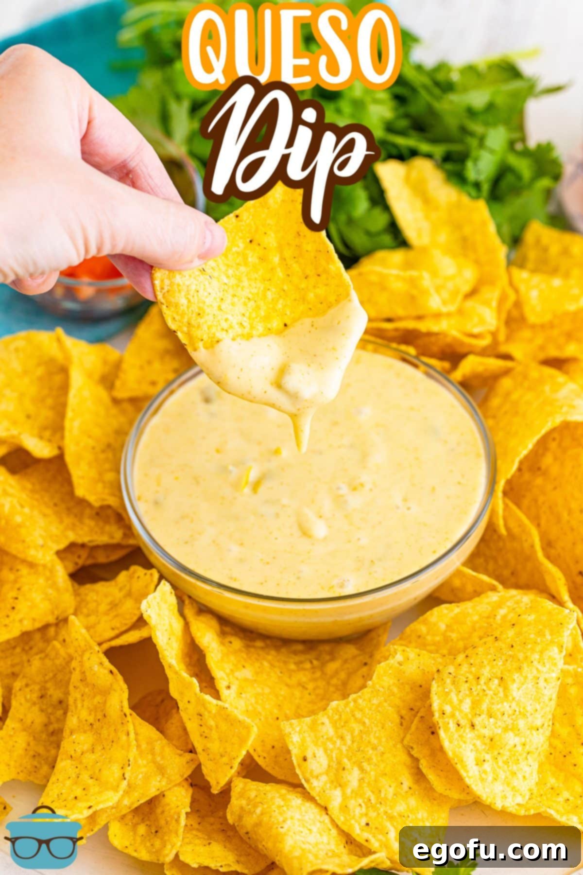 A crispy tortilla chip being generously dipped into a bowl of warm, homemade Queso Dip, showing off its rich, creamy texture.