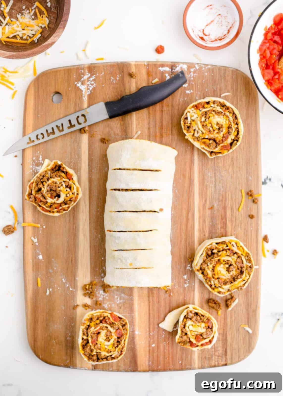 Zesty Taco Roll-Ups 11 A serrated knife expertly slicing the filled puff pastry log into uniform one-inch pinwheel pieces, revealing the layers of meat and cheese.