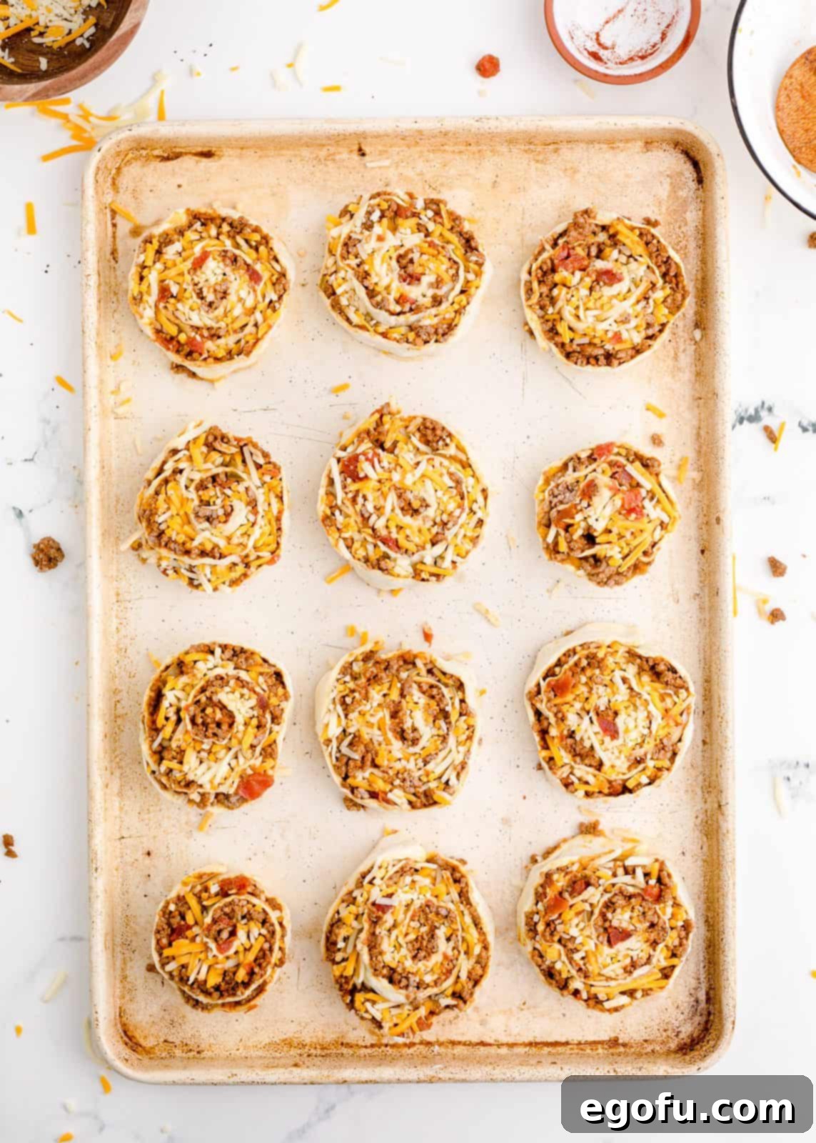 Zesty Taco Roll-Ups 12 Raw taco pinwheels neatly arranged on the prepared baking sheet, spaced out and ready to go into the oven.