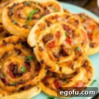 Zesty Taco Roll-Ups 14 Square image of stacked Taco Pinwheels on blue plate.