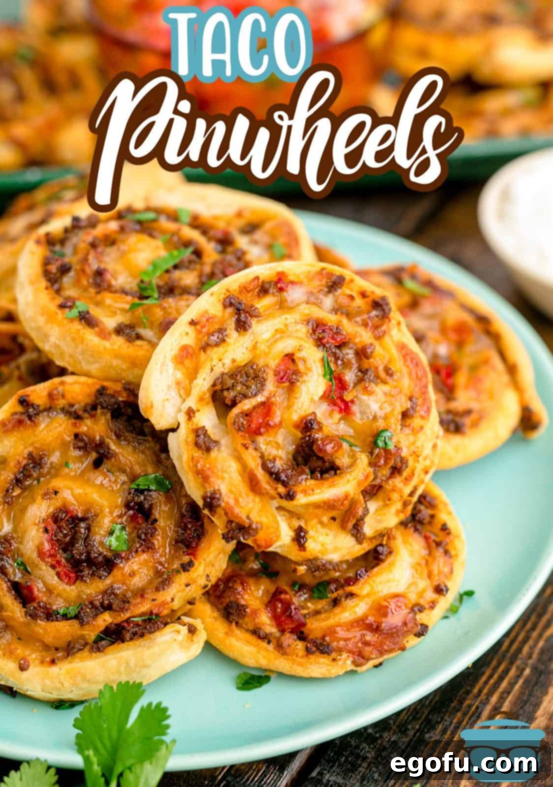 Zesty Taco Roll-Ups 3 A beautifully arranged blue plate overflowing with golden-brown Taco Pinwheels, garnished with fresh cilantro, ready for serving.