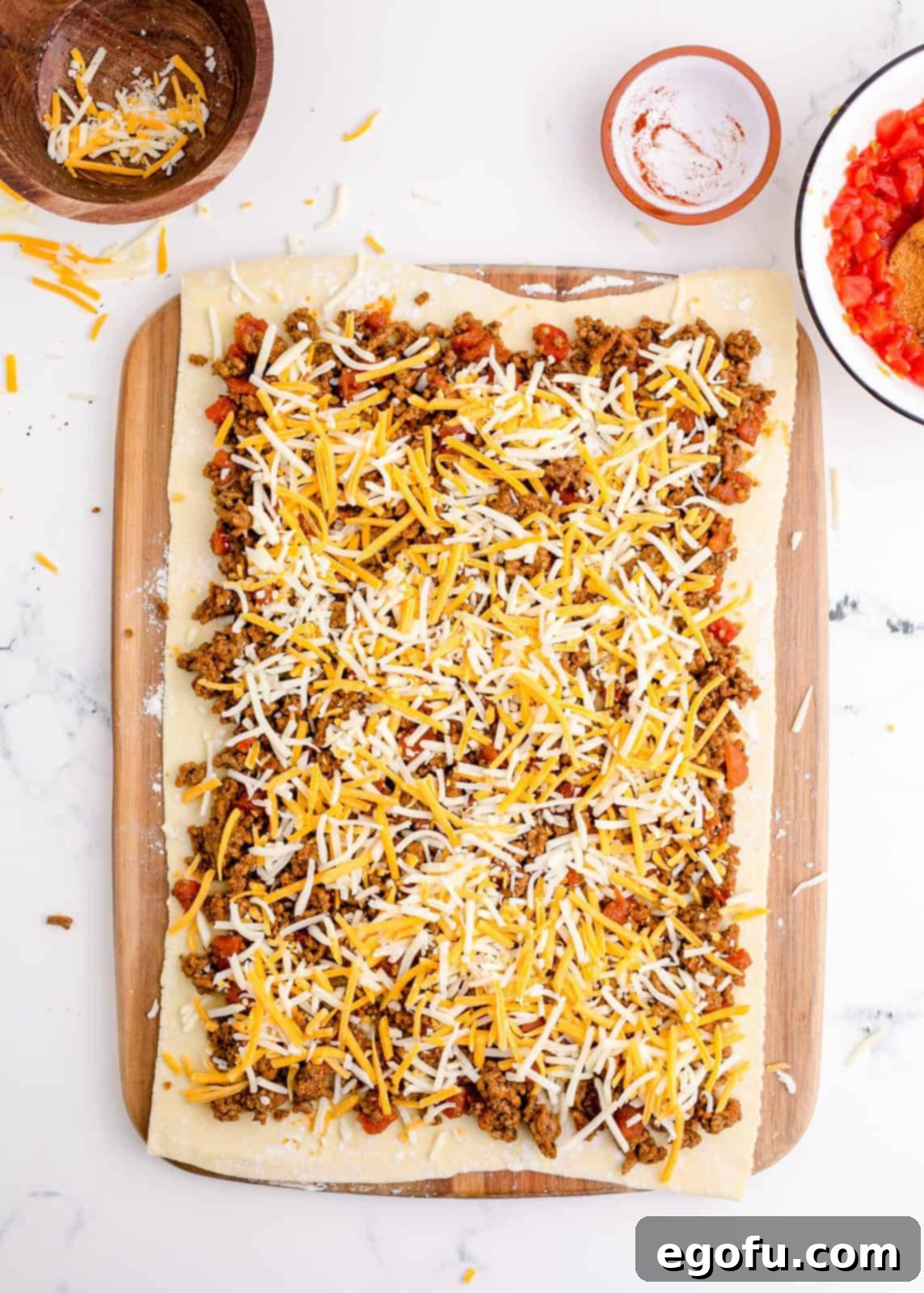 Zesty Taco Roll-Ups 9 The savory taco meat mixture and generous shredded cheese evenly spread across the puff pastry sheet, creating a vibrant filling.