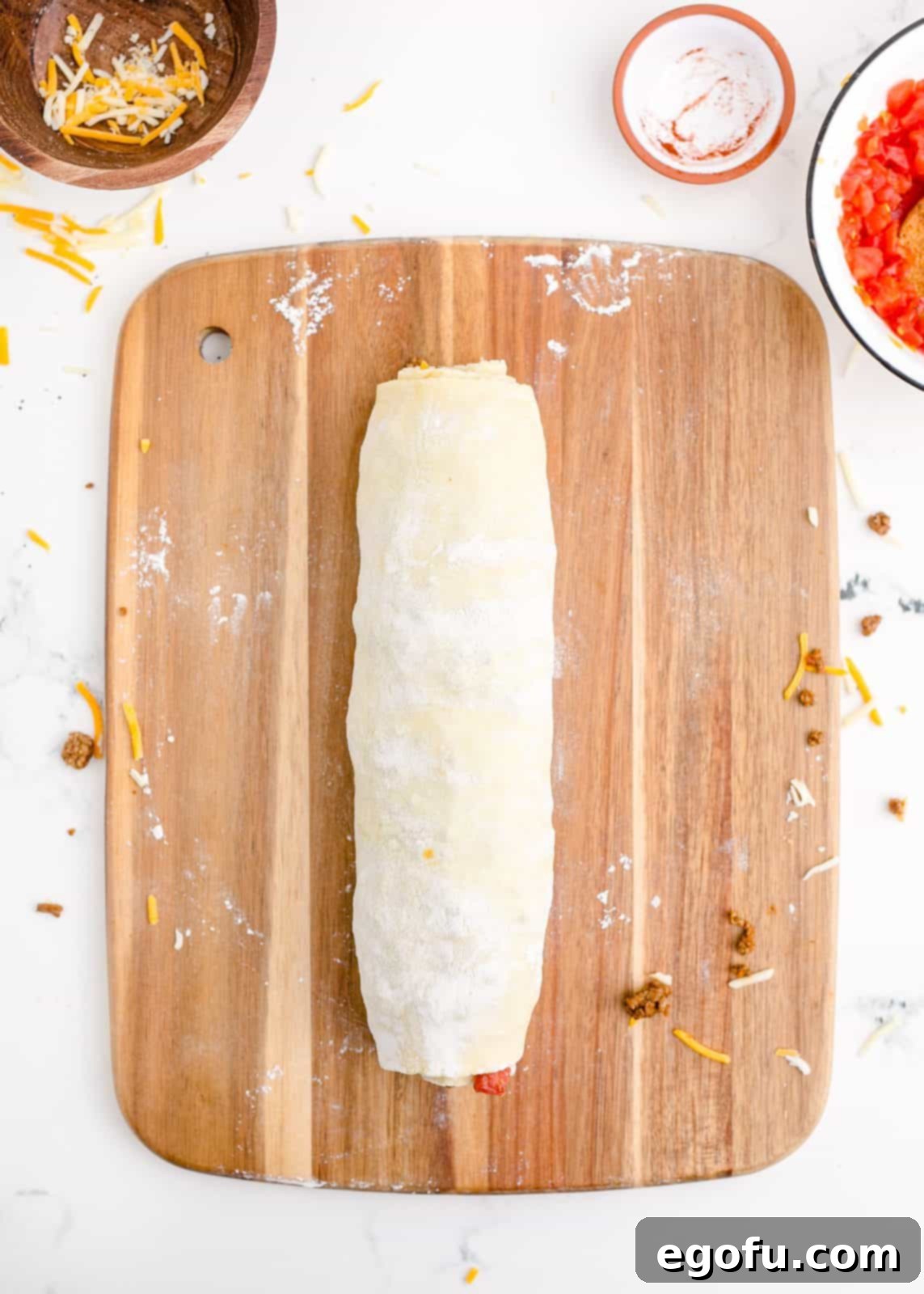 Zesty Taco Roll-Ups 10 The puff pastry, filled with taco mixture and cheese, expertly rolled up tightly into a perfect log, ready for slicing.