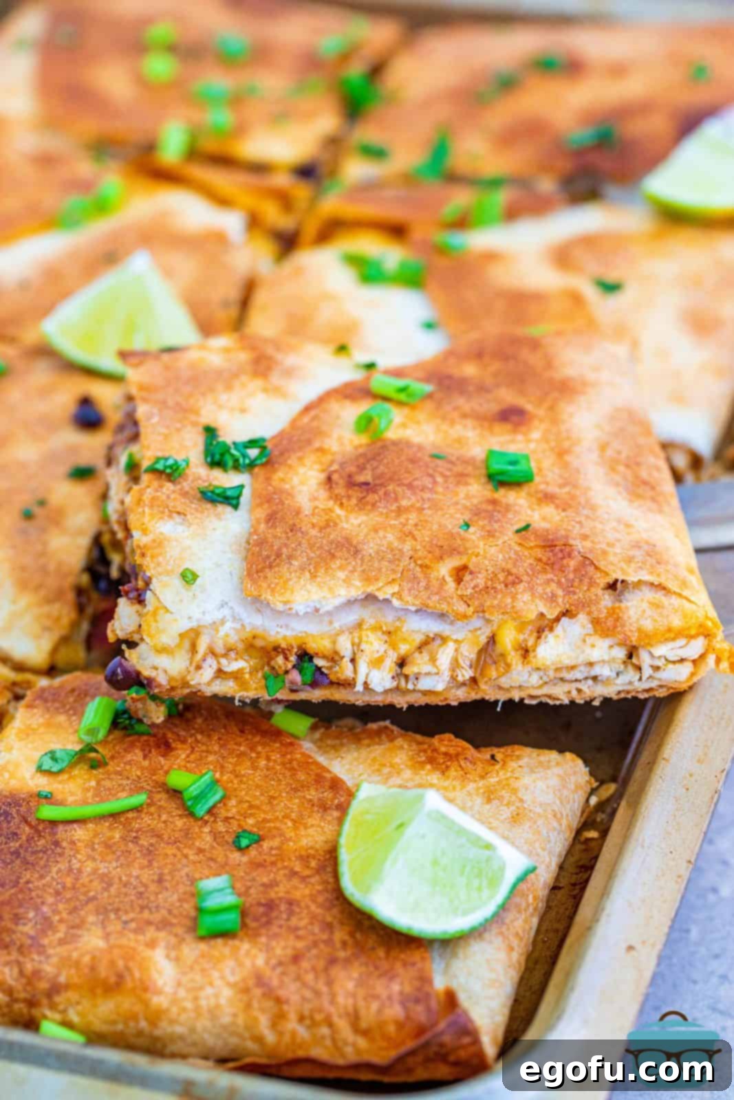 Delicious Sheet Pan Chicken Quesadillas, golden-brown and cut into triangles, resting on a baking sheet, ready to be served.