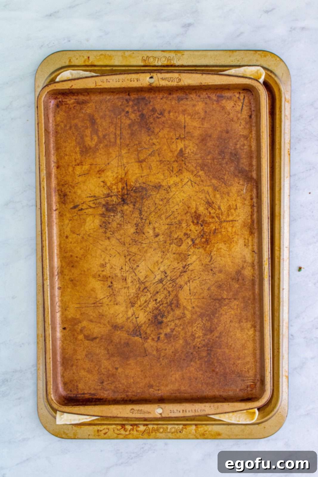 A second sheet pan placed directly on top of the buttered and folded quesadilla, ready to press it during baking for a perfectly crispy result.