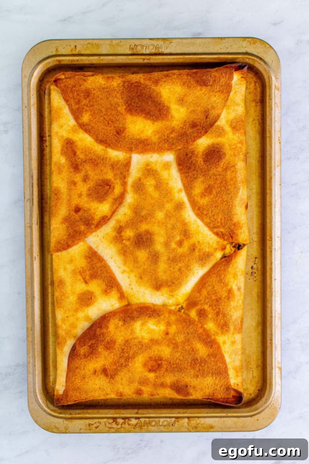 The finished Sheet Pan Chicken Quesadilla, freshly baked to a golden-brown crisp, just out of the oven and still on the baking sheet.