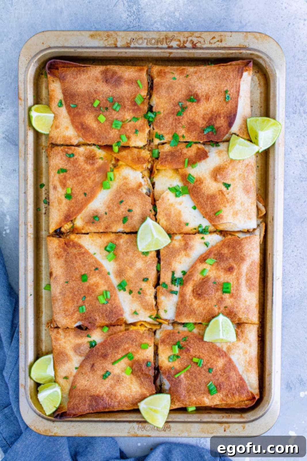 Freshly cut Sheet Pan Chicken Quesadillas arranged in the pan, garnished with cilantro and lime wedges, ready to be enjoyed.