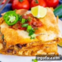 Square image of two stacked Sheet Pan Chicken Quesadillas on white plate with toppings.