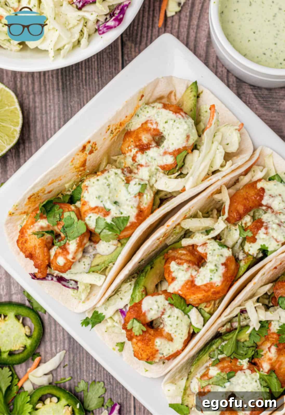 Overhead of three Shrimp Tacos on white plate with slaw.