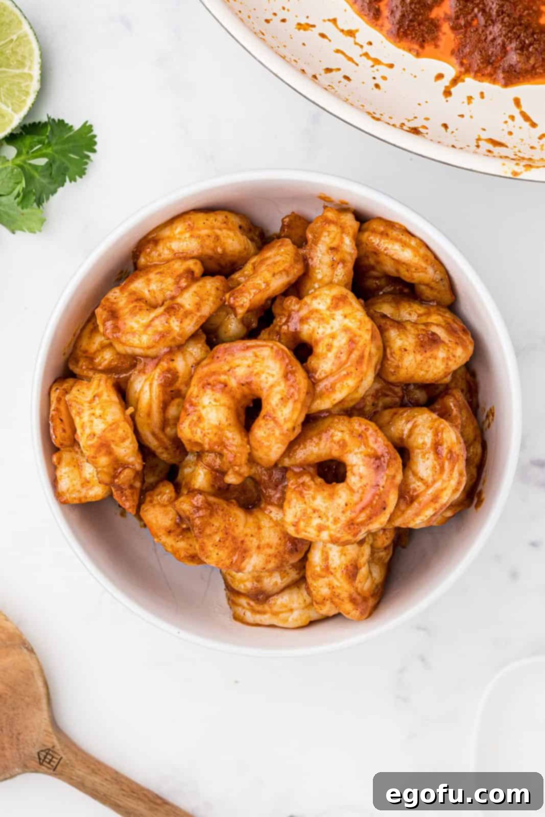 Taco seasoning mixture coating shrimp in bowl.