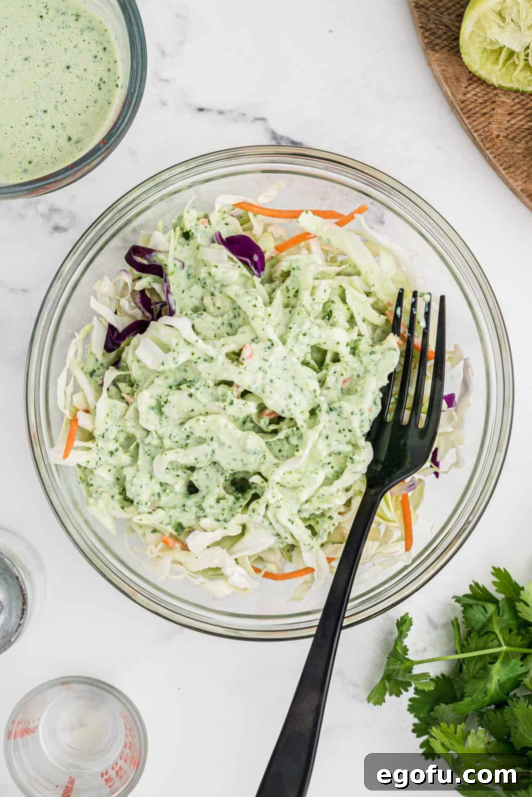 Sauce added to coleslaw mix in bowl.