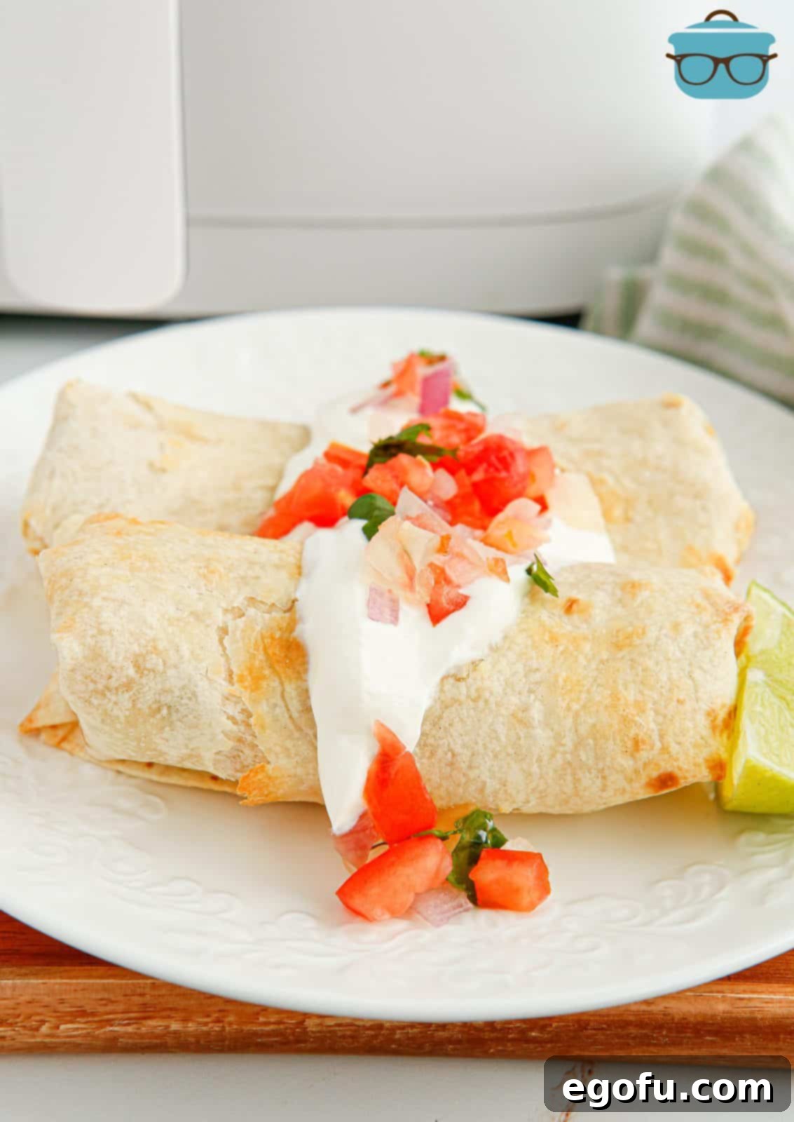 Air Fryer Chicken Chimichangas on plate topped with sour cream and pico de Gallo.