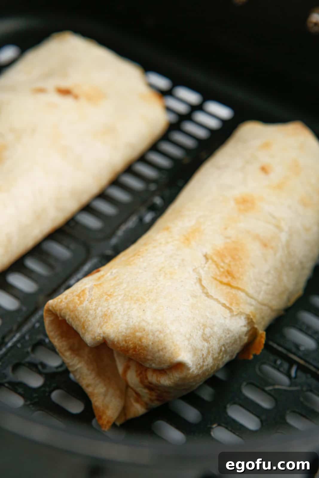 Finished Chimichangas in air fryer basket.