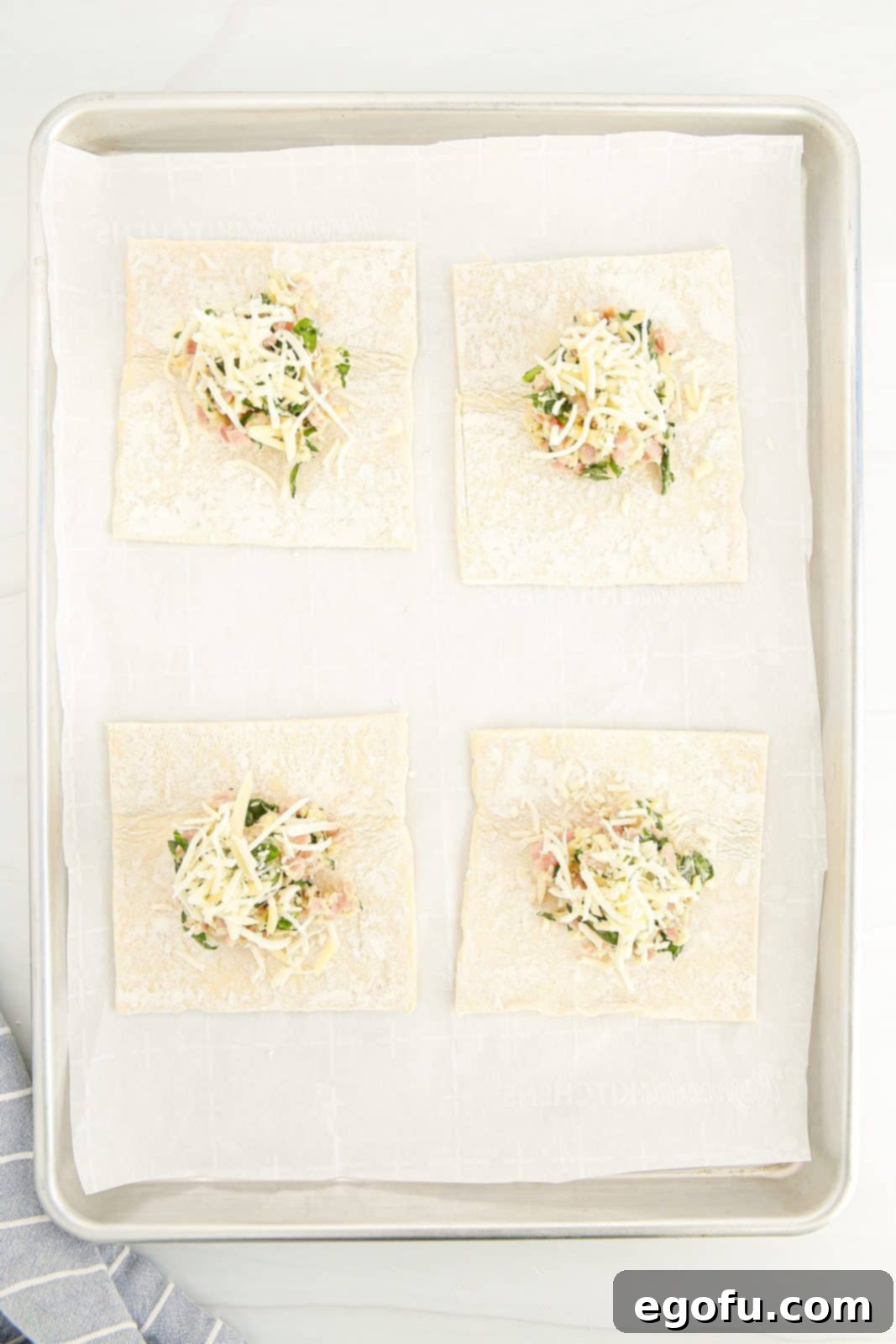 Additional cheese sprinkled on top of the filling mixture in puff pastry squares.