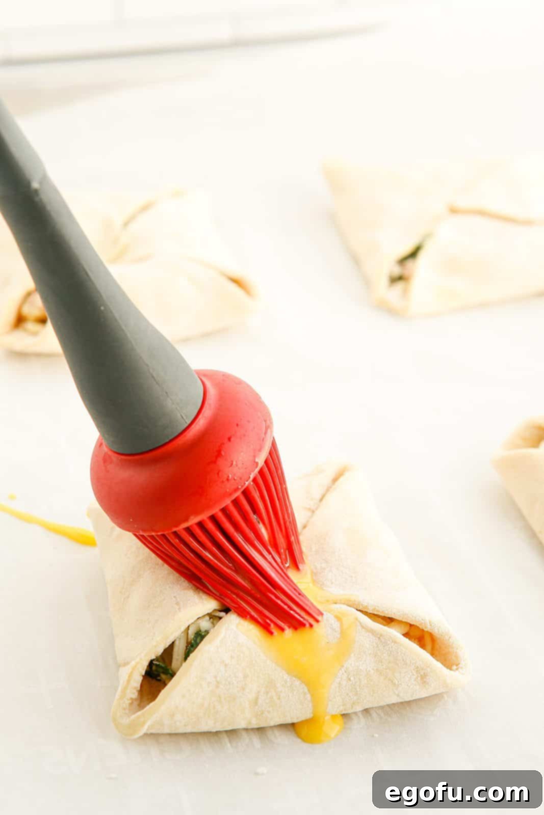 Puff pastry being brushed with egg mixture for a golden finish.