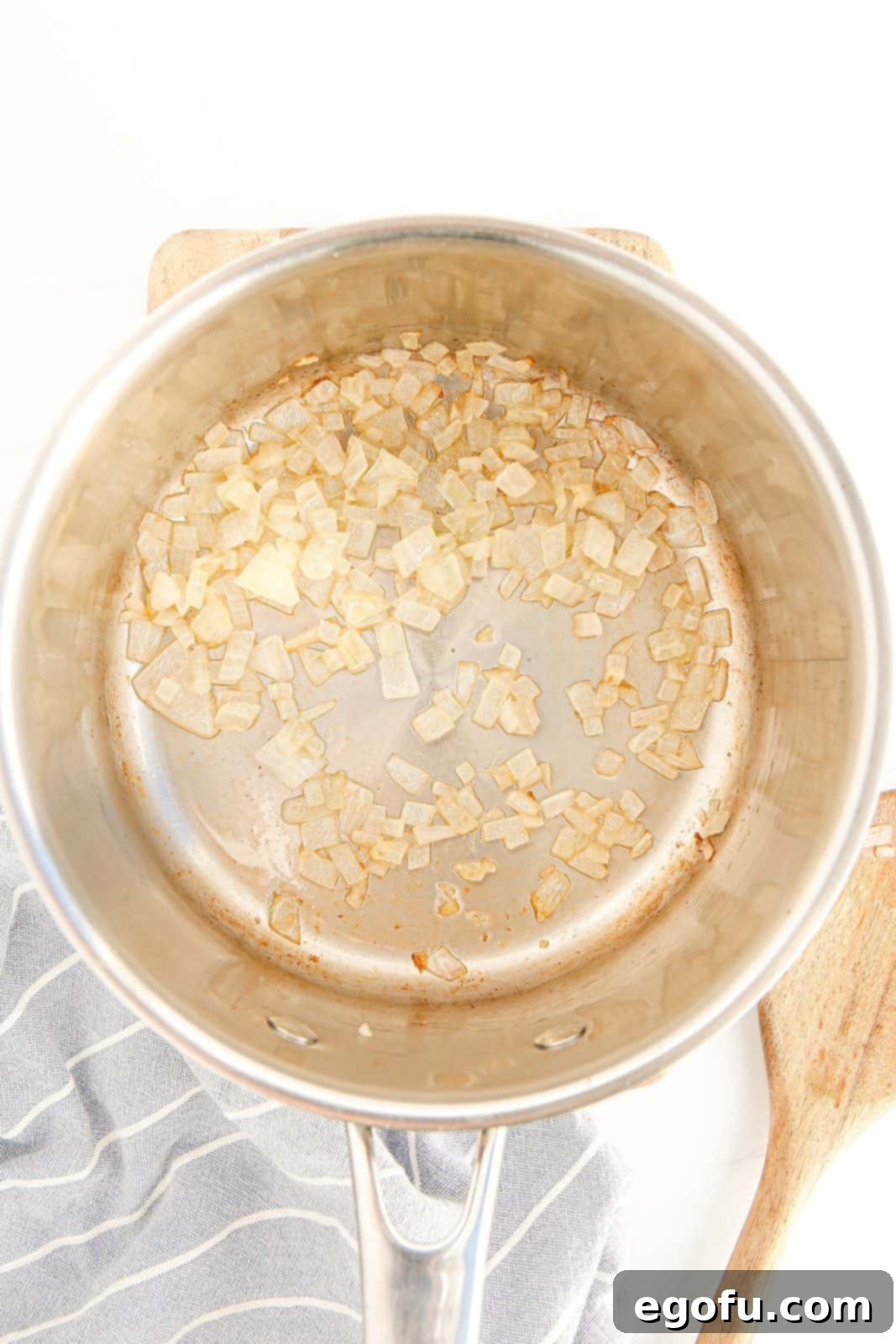Diced onions sautéing in melted butter in a pan until translucent.