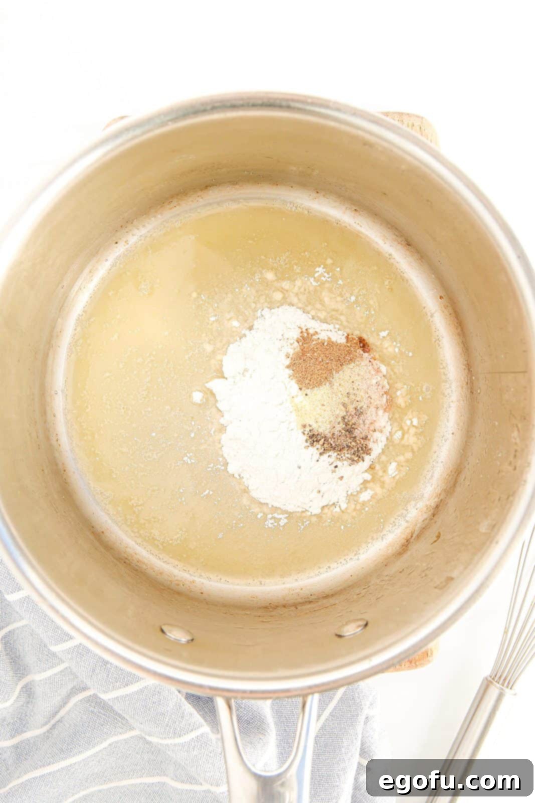 Flour incorporated into melted butter with salt, pepper, and garlic powder in a saucepan.