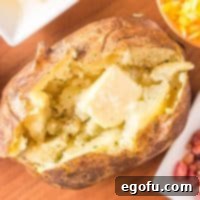 Square image of Grilled Baked Potatoes overhead with a pat of butter melting.
