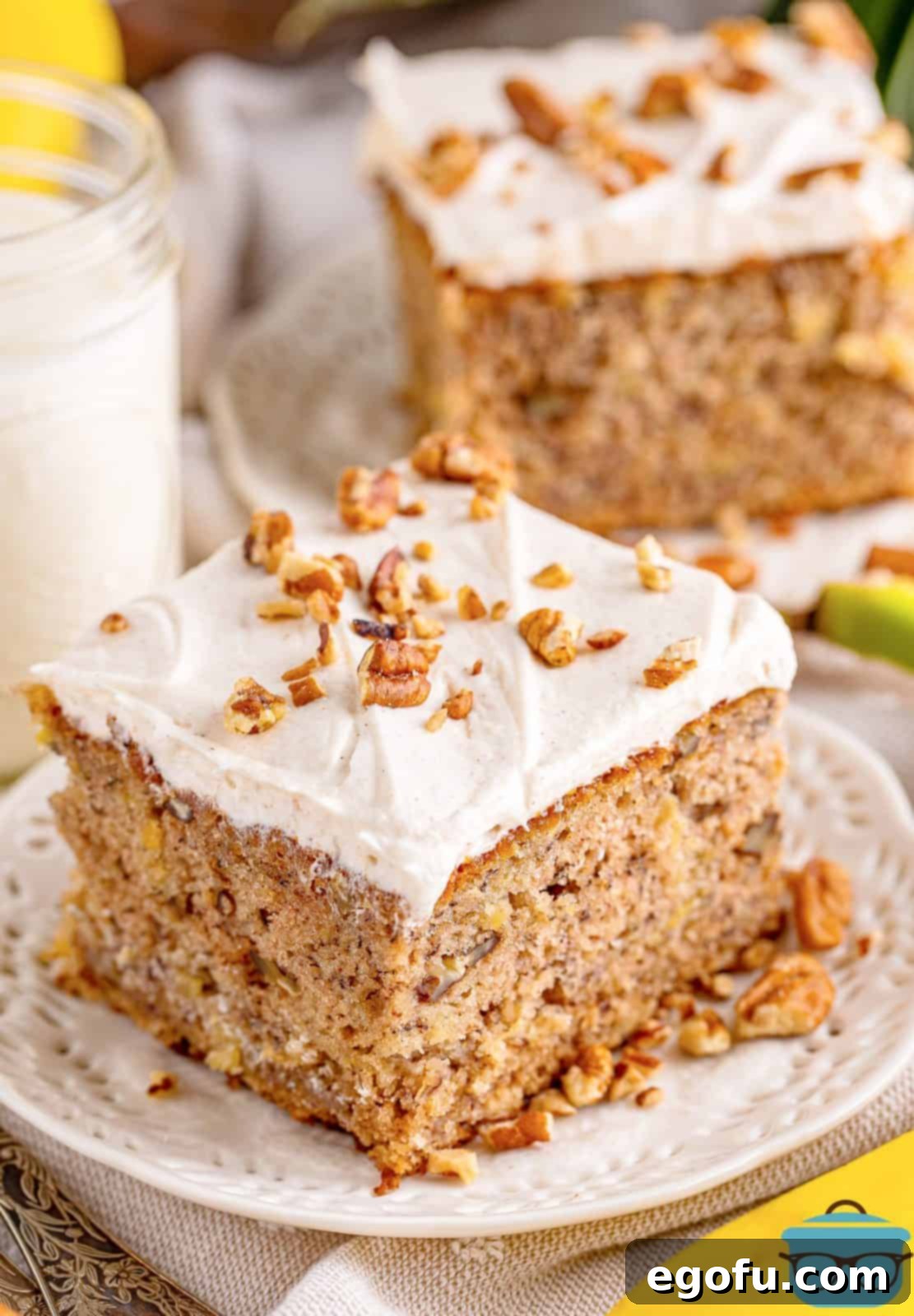 Southern Sunshine Cake 2 Two slices of Hummingbird Cake on white plate with chopped nuts around slices.
