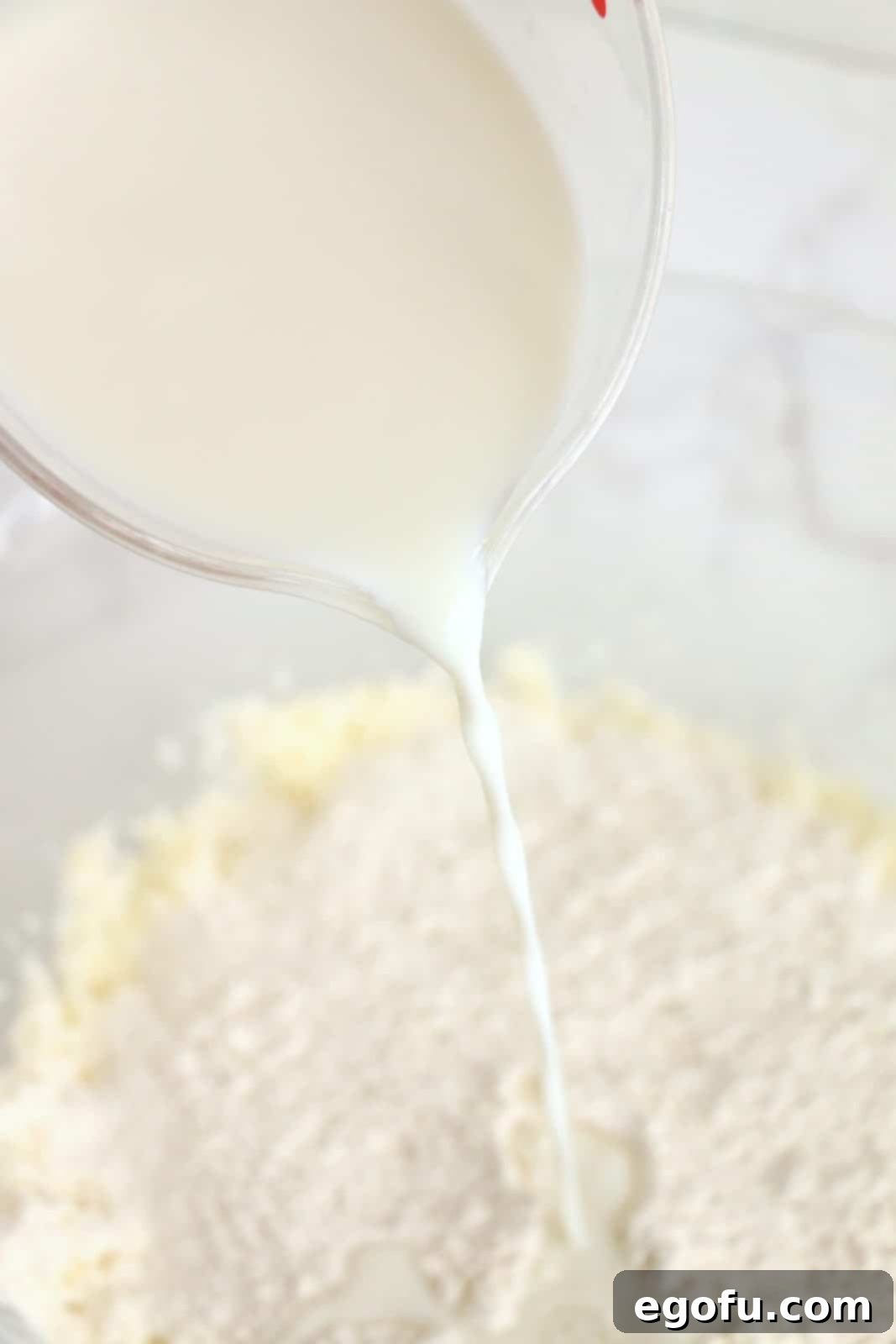 Flour and milk being alternated into batter mixture in bowl.