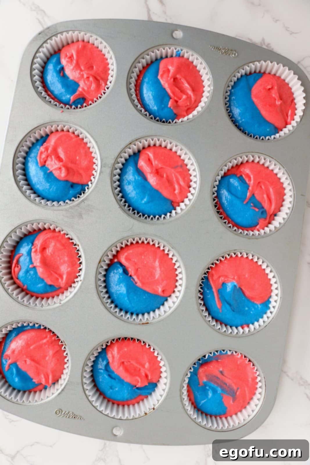 Red and blue batter placed into lined cupcake tin.