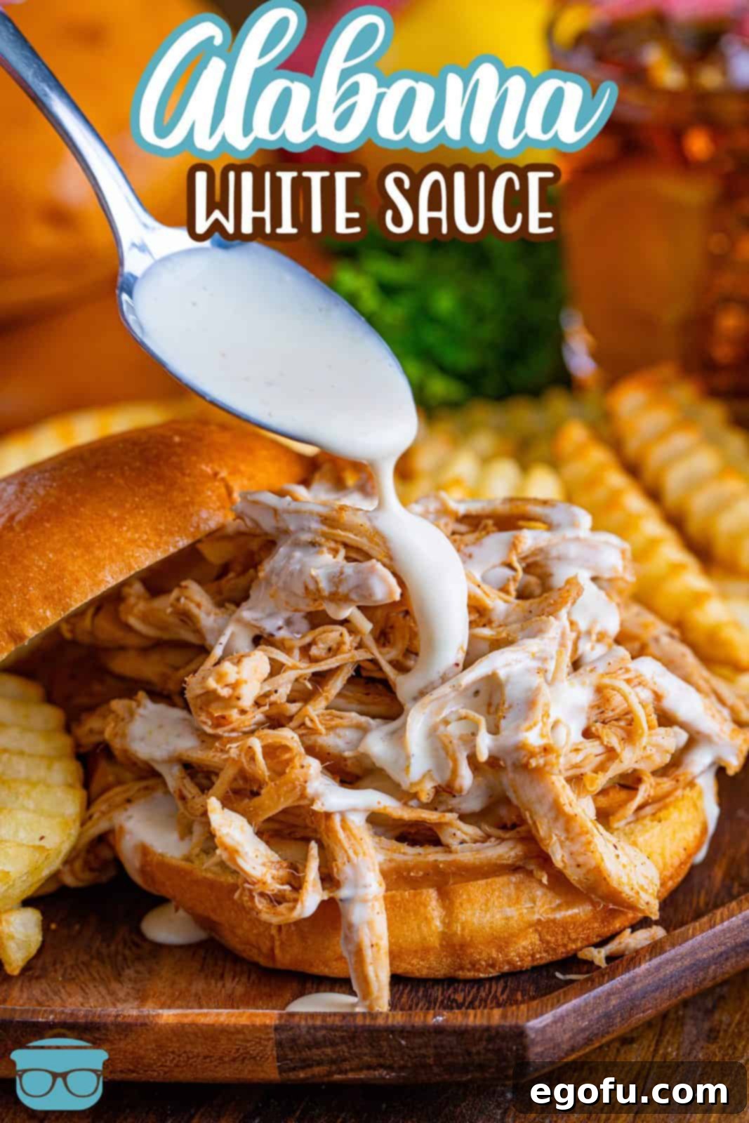The South's Signature White BBQ 3 Pinterest image of spoon drizzling Alabama White Sauce over bbq chicken sandwich.