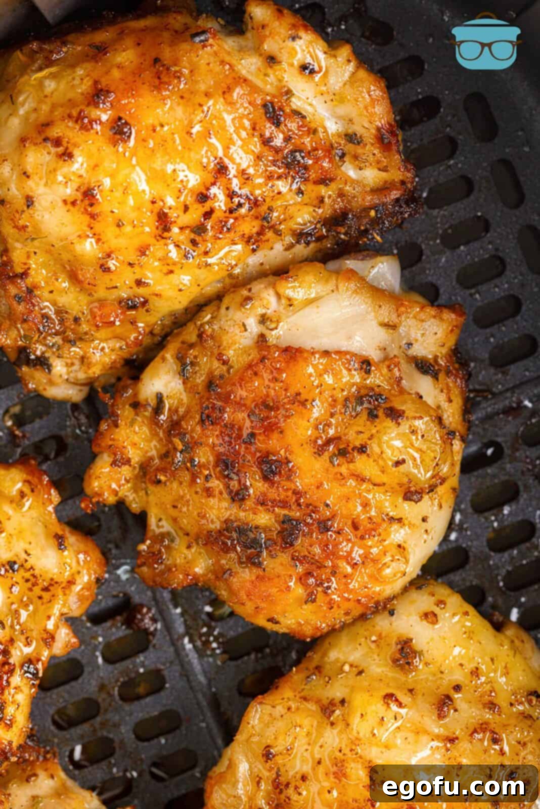 Crispy Lemon Pepper Air Fryer Chicken Thighs 2 Overhead photo of golden brown Air Fryer Lemon Pepper Chicken Thighs, garnished with fresh parsley and lemon slices, presented in an air fryer basket, emphasizing their crispy skin and juicy appearance.