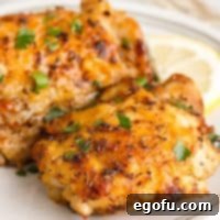 Crispy Lemon Pepper Air Fryer Chicken Thighs 16 Close-up square image of Air Fryer Lemon Pepper Chicken Thighs on a white plate, showing crispy skin and garnishes.